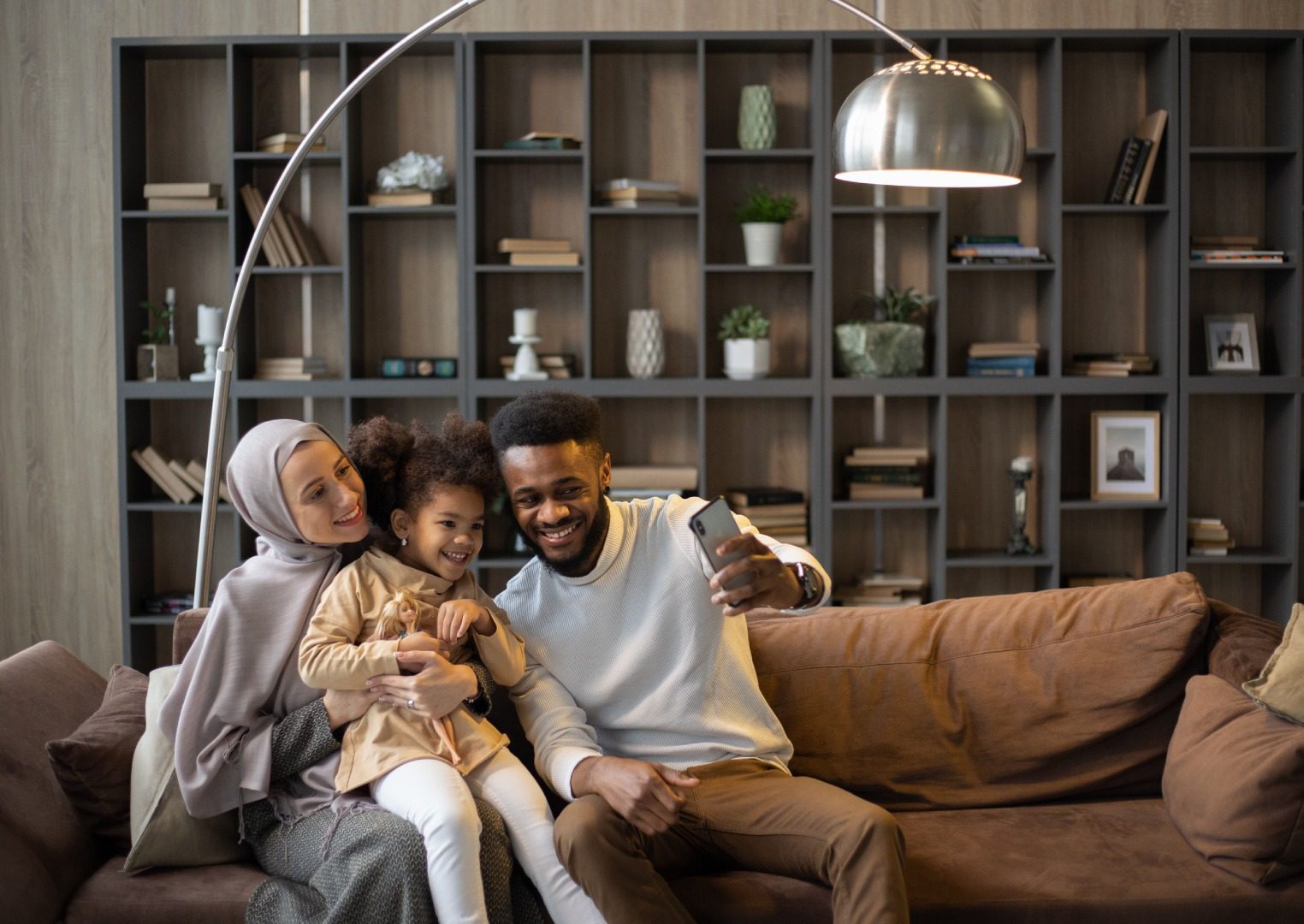 A man and woman sitting on top of a brown couch.