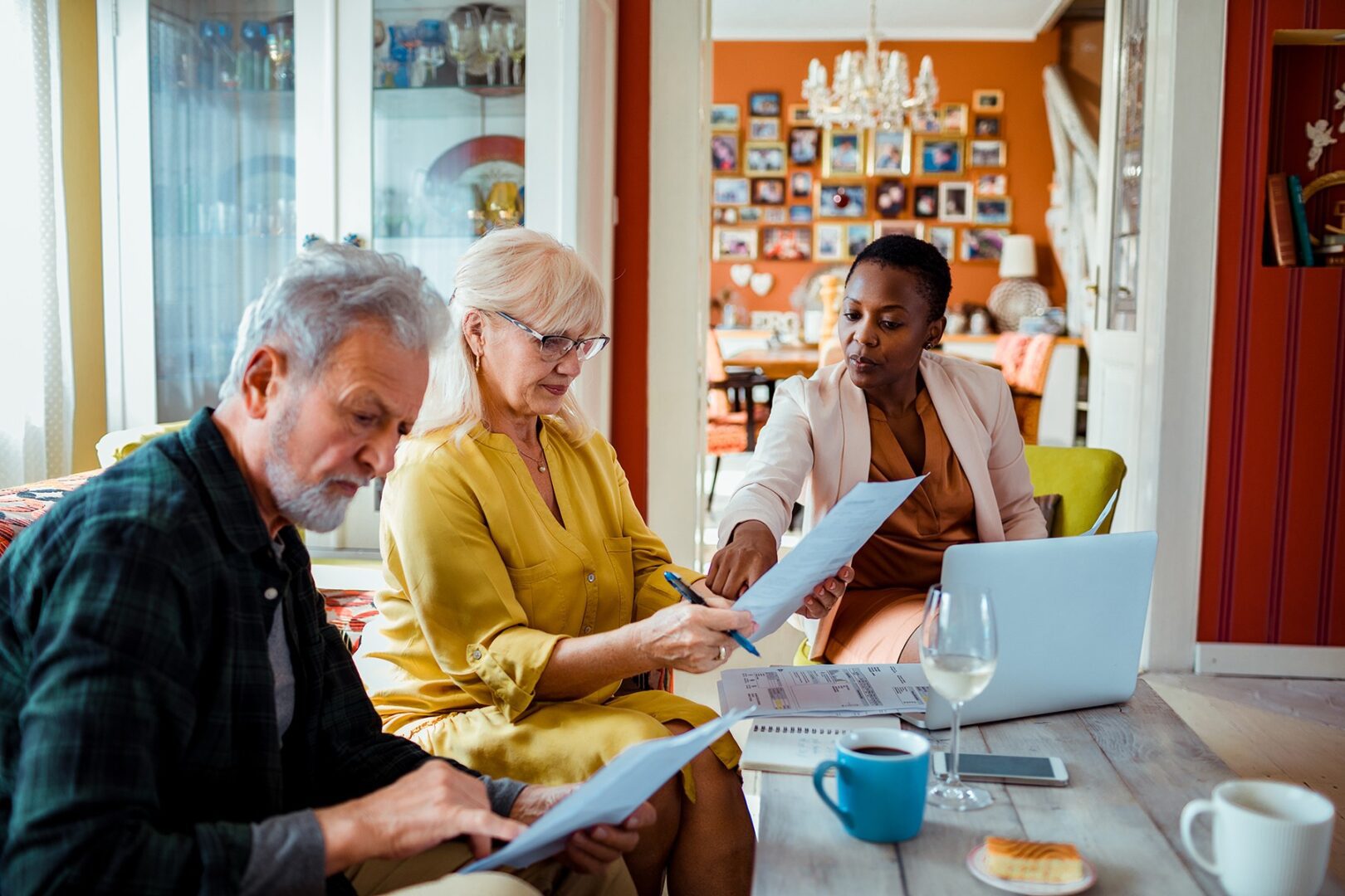 Three people sitting at a table with papers and laptops.